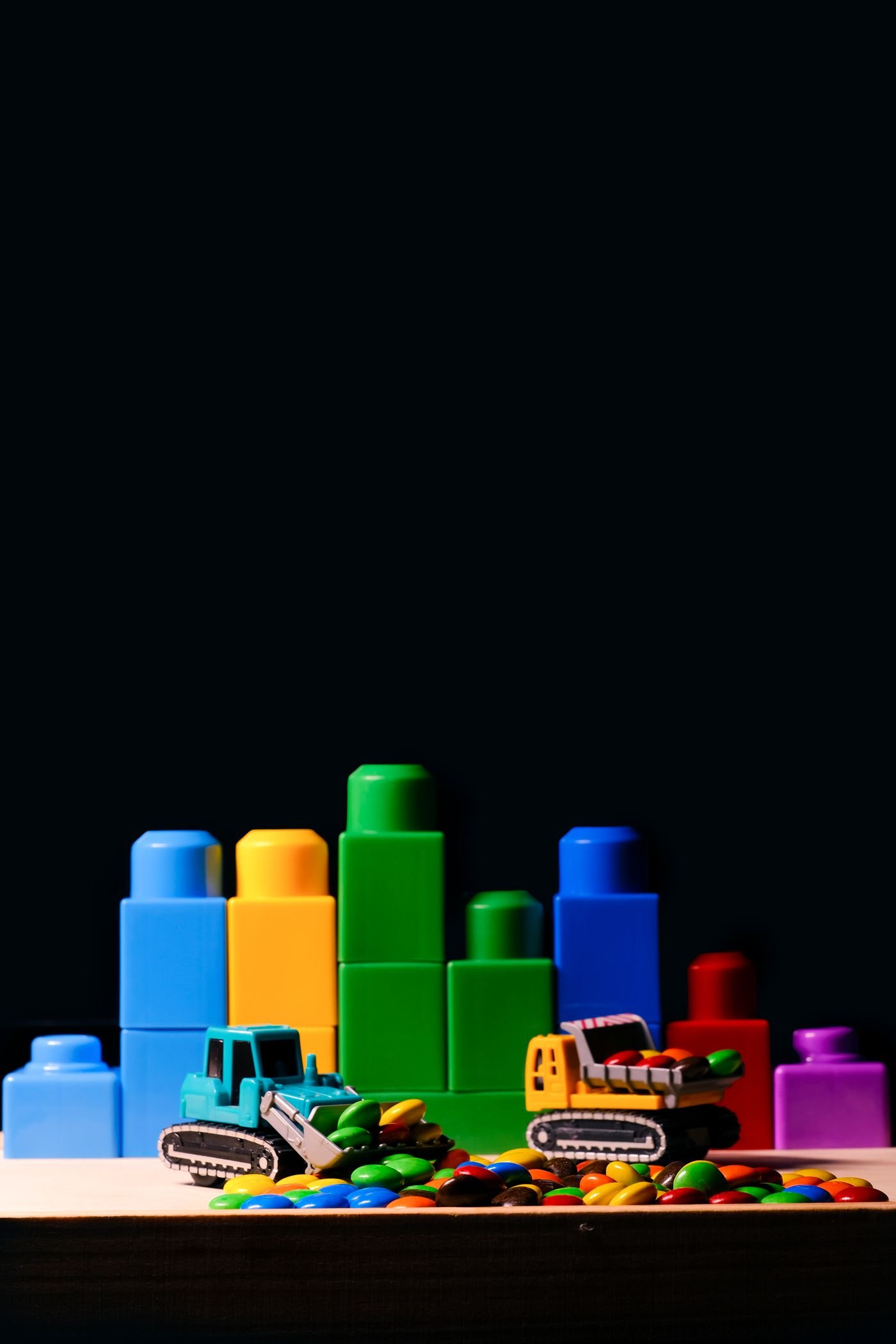 Colorful building blocks arranged on a dark studio background