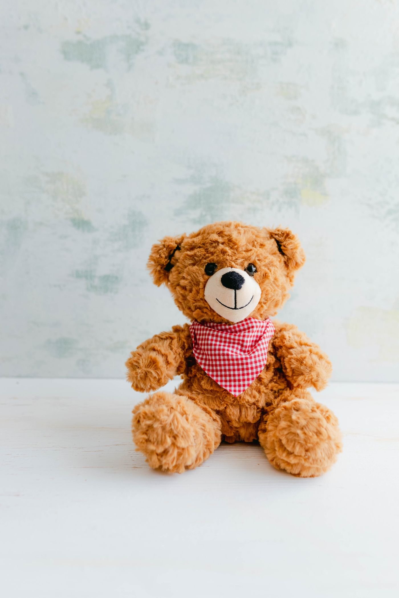 A soft brown teddy bear wearing a knitted hat