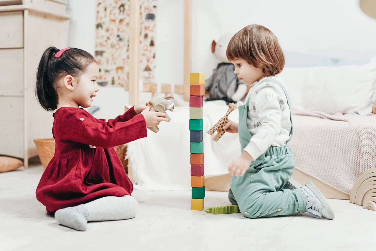 Two children happily playing together with wooden toy figurines