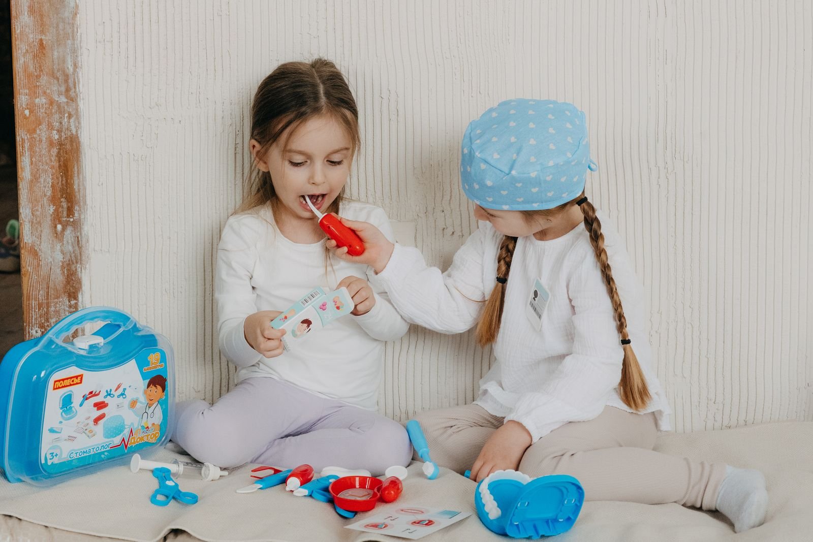Two children playing with toys together on a bed